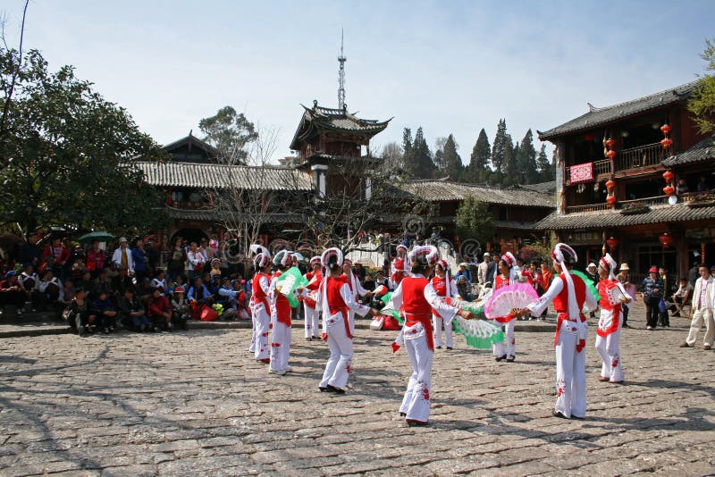 Os dançarinos tradicionais de um grupo minoritário executam na cidade velha de Lijiang imagem de stock Os dançarinos tradicionais de um grupo minoritário executam na cidade velha de Lijiang imagem de stock