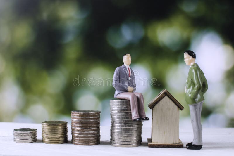 Os executivos modelam com moedas e casa do dinheiro imagem de stock Os executivos modelam com moedas e casa do dinheiro imagem de stock