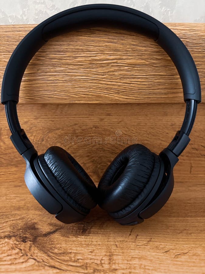 Os fones de ouvido pretos estão em uma prateleira de madeira. fotos de stock