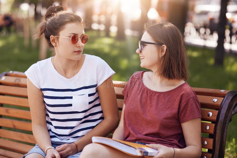 Os groupmates fêmeas amigáveis felizes encontrar-se, para olhar o ech outro quando tenha a conversa agradável, vestido em camisas foto de stock Os groupmates fêmeas amigáveis felizes encontrar-se, para olhar o ech outro quando tenha a conversa agradável, vestido em camisas foto de stock