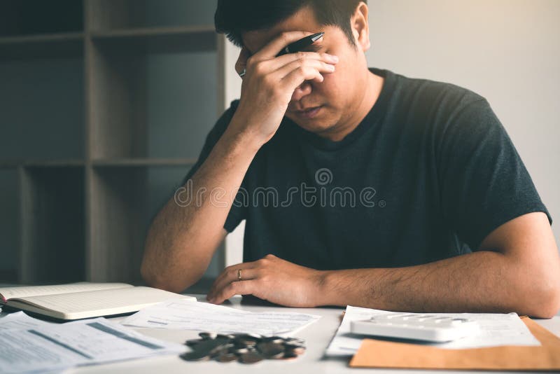 Os homens asiáticos são forçados sobre problemas financeiros, com as faturas e as calculadoras colocadas na tabela ao ter o esfor fotografia de stock royalty free Os homens asiáticos são forçados sobre problemas financeiros, com as faturas e as calculadoras colocadas na tabela ao ter o esfor fotografia de stock royalty free