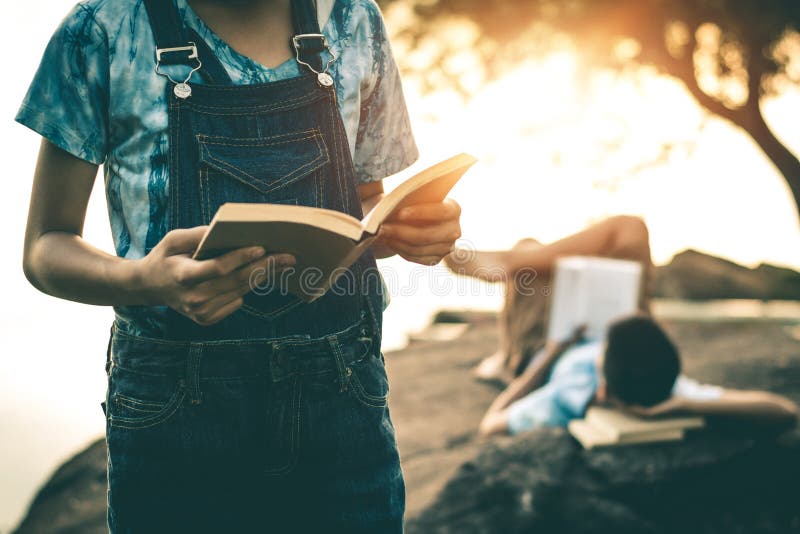Os homens e as mulheres leram livros na natureza quieta fotografia de stock Os homens e as mulheres leram livros na natureza quieta fotografia de stock