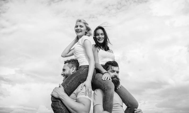 Os homens levam amigas em ombros F?rias e divertimento de ver?o Pares na data dobro Convidando uns outros pares para juntar-se fotografia de stock Os homens levam amigas em ombros F?rias e divertimento de ver?o Pares na data dobro Convidando uns outros pares para juntar-se fotografia de stock