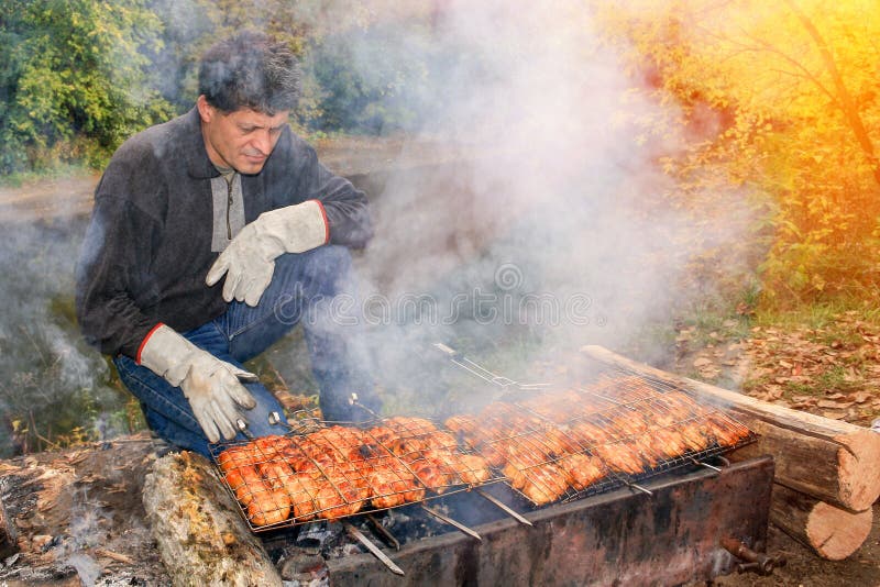 Os homens maduros consider?veis fazem o assado delicioso na grade fotografia de stock Os homens maduros consider?veis fazem o assado delicioso na grade fotografia de stock