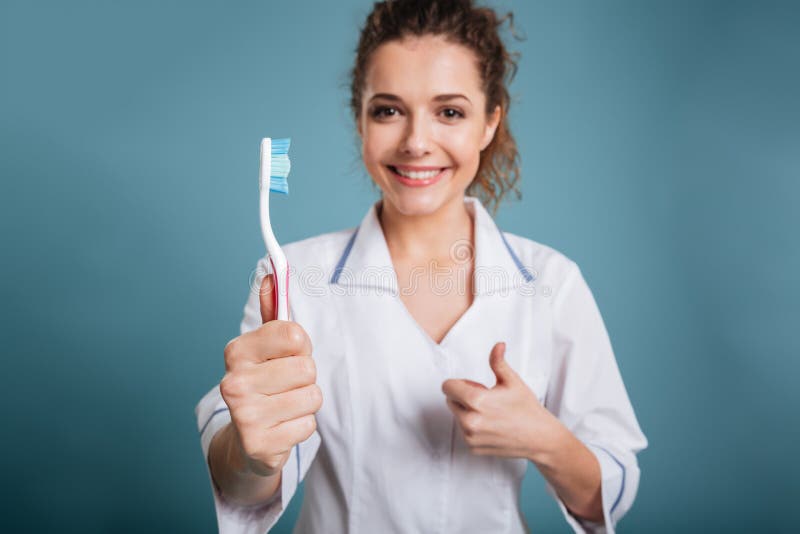 Os jovens de sorriso nutrem manter a escova de dentes e mostrar os polegares foto de stock Os jovens de sorriso nutrem manter a escova de dentes e mostrar os polegares foto de stock
