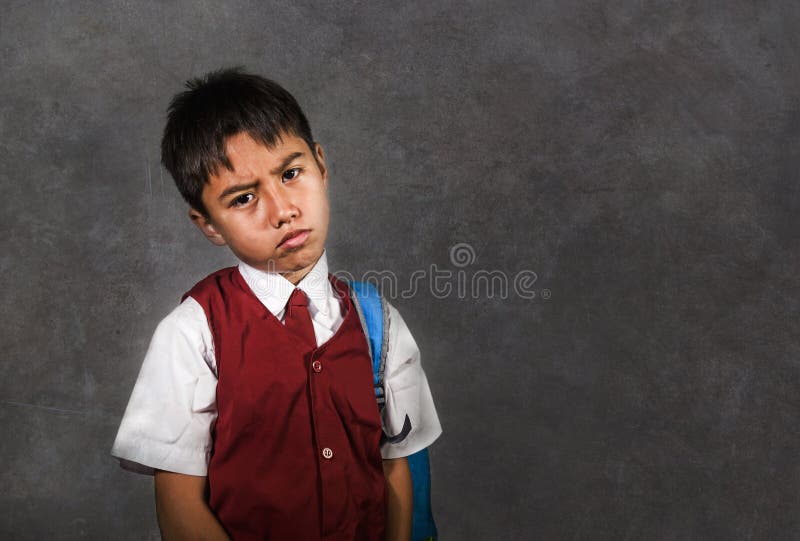 Os jovens tiranizados abusaram a estudante em deprimido triste levando uniforme do saco de escola no quadro-negro que sente uma v fotografia de stock royalty free Os jovens tiranizados abusaram a estudante em deprimido triste levando uniforme do saco de escola no quadro-negro que sente uma v fotografia de stock royalty free
