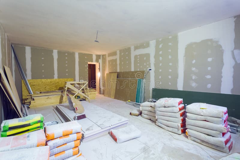 Os materiais para blocos da massa de vidraceiro da construção, folhas da placa de gesso ou drywall no apartamento estão sob a con imagem de stock royalty free Os materiais para blocos da massa de vidraceiro da construção, folhas da placa de gesso ou drywall no apartamento estão sob a con imagem de stock royalty free
