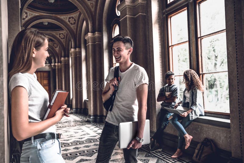 Os melhores amigos Os estudantes de sorriso novos que estão no salão da universidade e falam um com o otro fotos de stock Os melhores amigos Os estudantes de sorriso novos que estão no salão da universidade e falam um com o otro fotos de stock