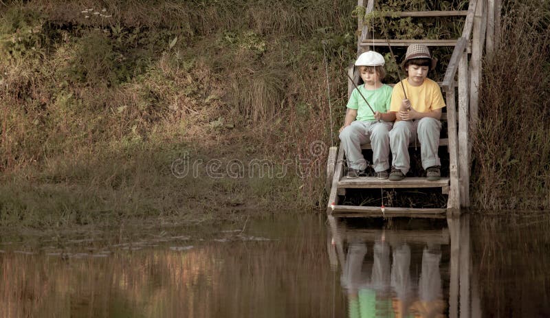 Os meninos felizes vão pescar no rio, duas crianças do pescador com uma vara de pesca na costa do lago imagens de stock royalty free Os meninos felizes vão pescar no rio, duas crianças do pescador com uma vara de pesca na costa do lago imagens de stock royalty free