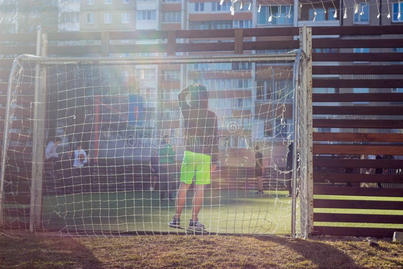 Os meninos jogam no p?tio em um campo de futebol especialmente equipado no fundo dos pr?dios de apartamentos imagens de stock Os meninos jogam no p?tio em um campo de futebol especialmente equipado no fundo dos pr?dios de apartamentos imagens de stock