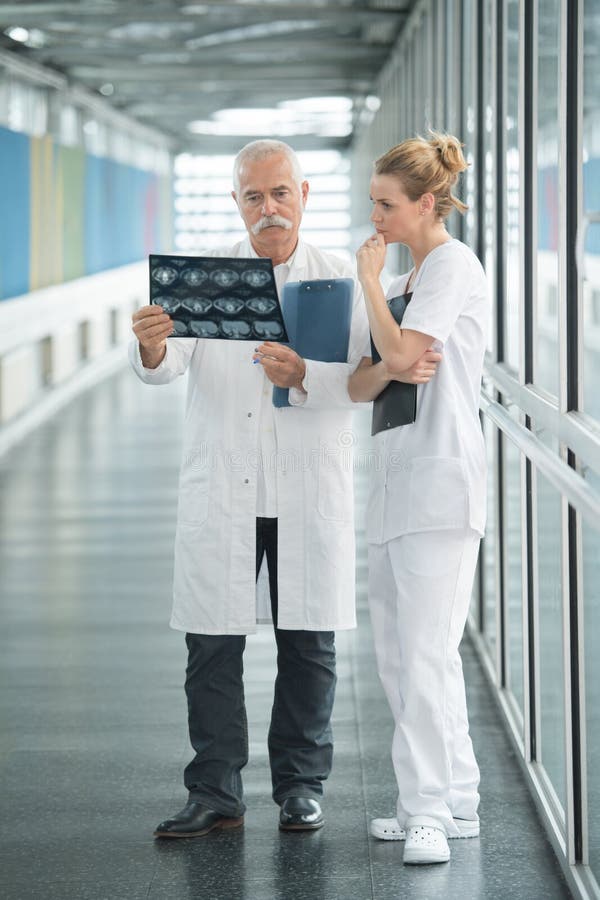 Medics looking at x-ray scan at hospitals corridor xray. Medics looking at x-ray scan at hospitals corridor xray