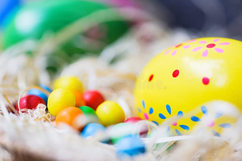 Os ovos da páscoa no fundo da cesta do ninho pintaram o ovo colorido decorado com os doces coloridos dos doces fotografia de stock royalty free Os ovos da páscoa no fundo da cesta do ninho pintaram o ovo colorido decorado com os doces coloridos dos doces fotografia de stock royalty free