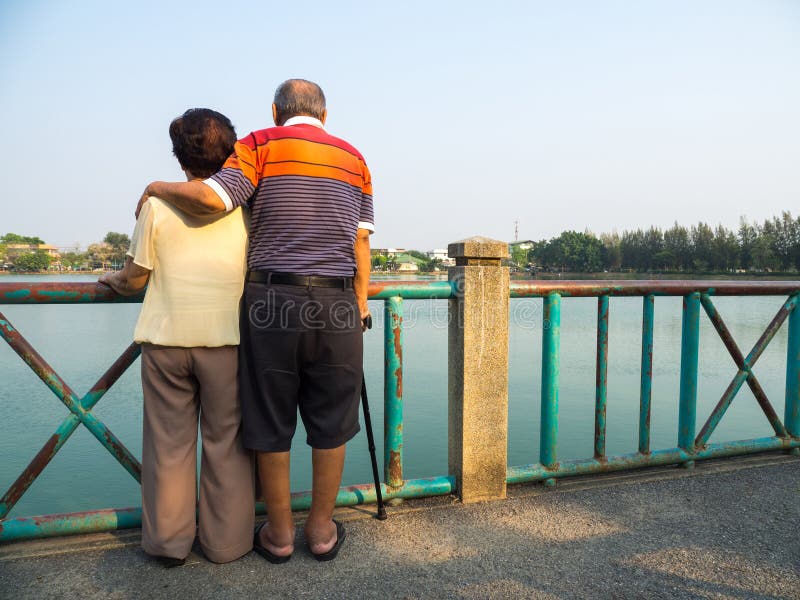Os pares asiáticos superiores românticos felizes estão na ponte na frente do lago O marido está com sua esposa Conceito do coupl foto de stock Os pares asiáticos superiores românticos felizes estão na ponte na frente do lago O marido está com sua esposa Conceito do coupl foto de stock
