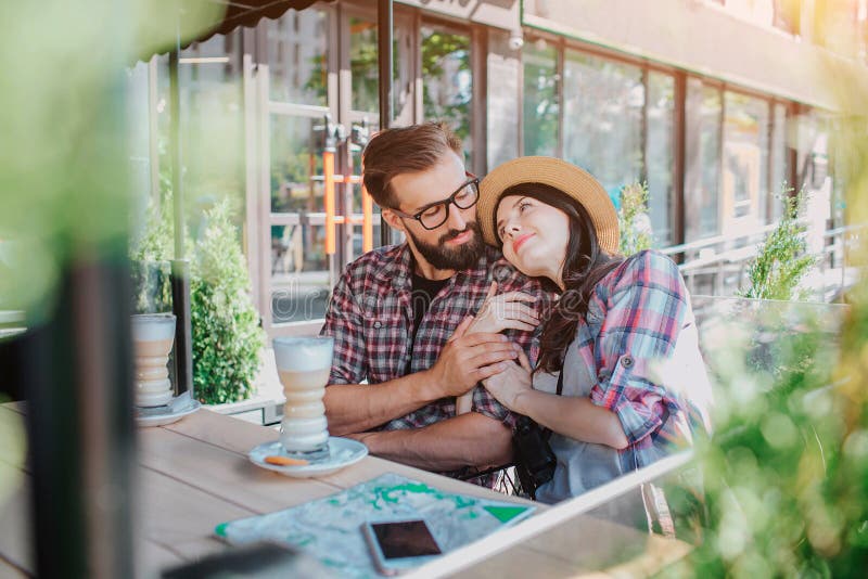 Os pares bonitos e surpreendentes sentam-se junto Inclina-se lhe Olham se e sorriem Guarda sua mão lá imagem de stock Os pares bonitos e surpreendentes sentam-se junto Inclina-se lhe Olham se e sorriem Guarda sua mão lá imagem de stock