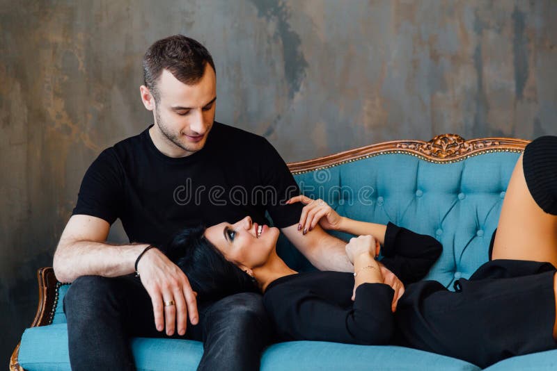 Os pares bonitos novos na roupa escura em um vintage de turquesa deitam imagem de stock Os pares bonitos novos na roupa escura em um vintage de turquesa deitam imagem de stock