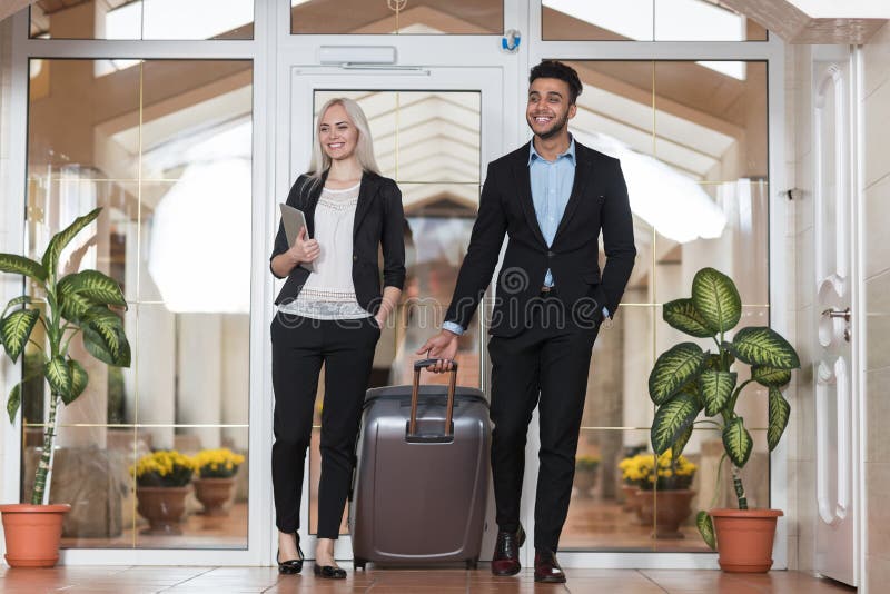 Os pares do negócio na entrada do hotel, no homem do grupo dos empresários e nos convidados da mulher chegam imagens de stock Os pares do negócio na entrada do hotel, no homem do grupo dos empresários e nos convidados da mulher chegam imagens de stock