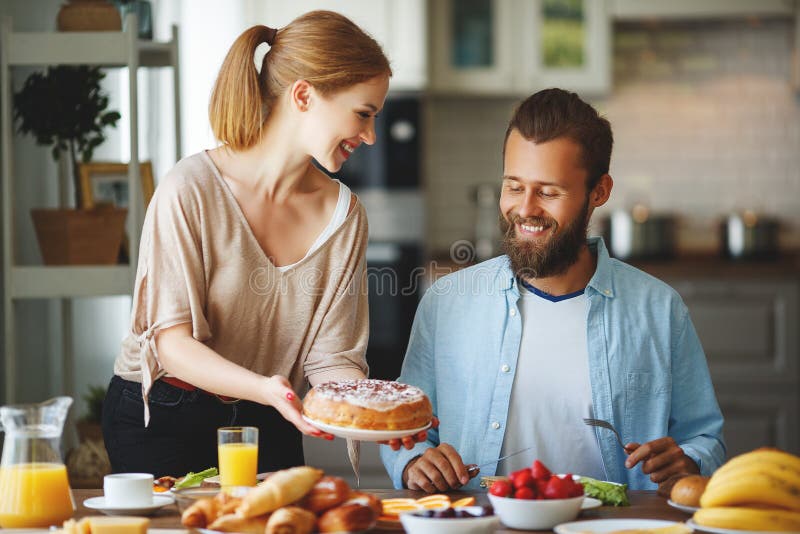Os pares felizes da família têm o café da manhã na cozinha na manhã foto de stock royalty free Os pares felizes da família têm o café da manhã na cozinha na manhã foto de stock royalty free