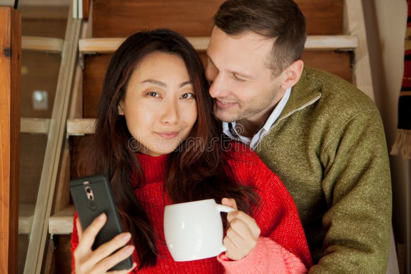 Os pares felizes sentam-se no fundo das escadas do apartamento novo fotografia de stock Os pares felizes sentam-se no fundo das escadas do apartamento novo fotografia de stock