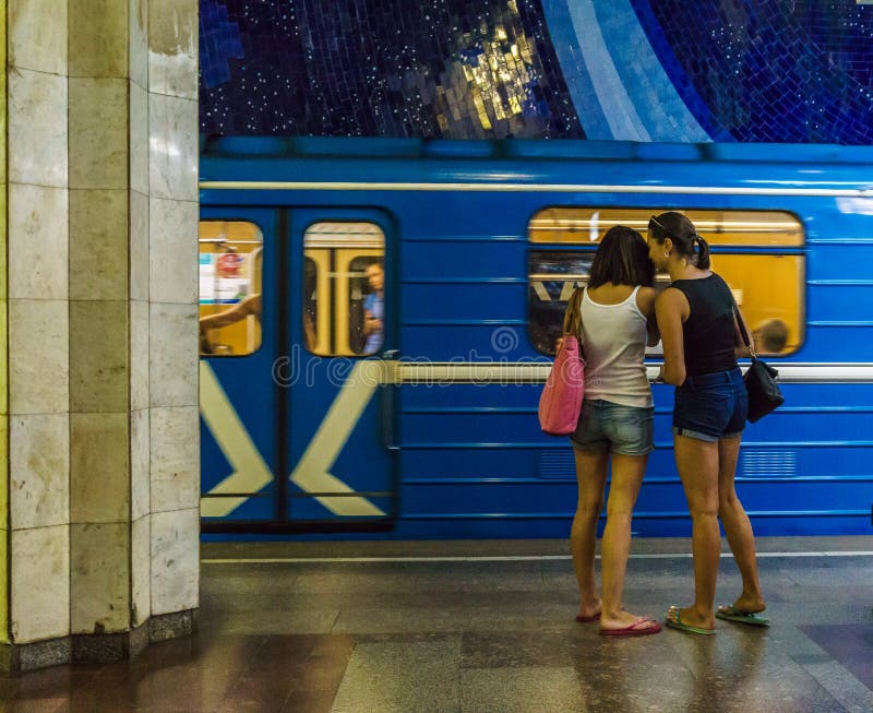 Os pares lésbicas que estão na estação subterrânea no fundo da equitação treinam imagem de stock Os pares lésbicas que estão na estação subterrânea no fundo da equitação treinam imagem de stock