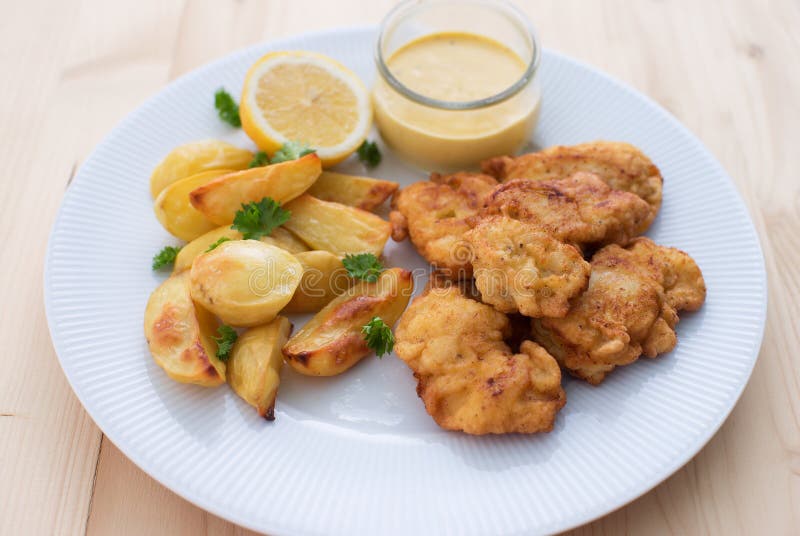 Os peixes de bacalhau nos fritos da massa ou do bacalhau servidos com as batatas cozidas com folhas da salsa e a casa fizeram o m imagem de stock Os peixes de bacalhau nos fritos da massa ou do bacalhau servidos com as batatas cozidas com folhas da salsa e a casa fizeram o m imagem de stock