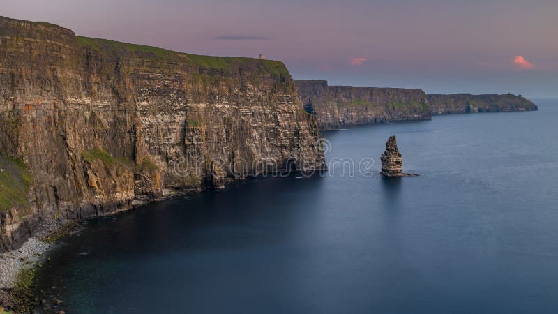 Os penhascos impressionantes e majestosos de Moher no condado Clare, Irlanda no por do sol, céu cor-de-rosa bonito imagem de stock royalty free Os penhascos impressionantes e majestosos de Moher no condado Clare, Irlanda no por do sol, céu cor-de-rosa bonito imagem de stock royalty free