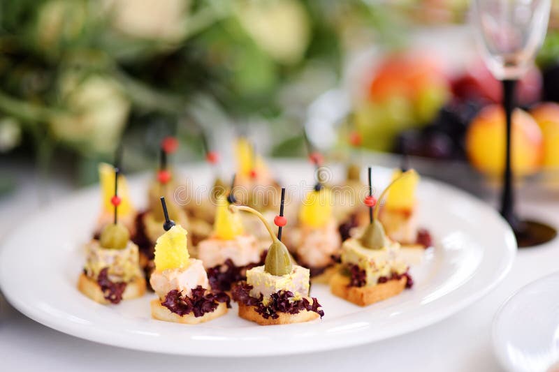 Os petiscos deliciosos do canape com cobertura do abacaxi e das alcaparras serviram em um partido ou em um copo de água fotos de stock royalty free Os petiscos deliciosos do canape com cobertura do abacaxi e das alcaparras serviram em um partido ou em um copo de água fotos de stock royalty free