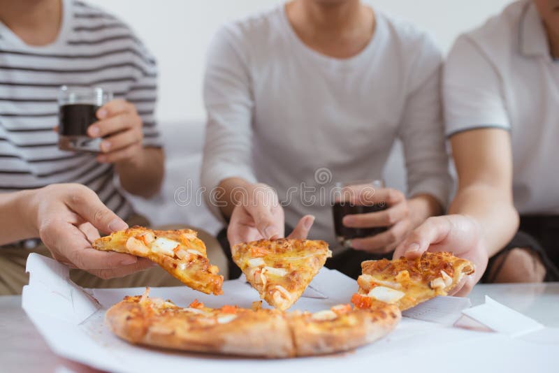 Os povos comem o fast food Mãos dos amigos que tomam fatias de pizza