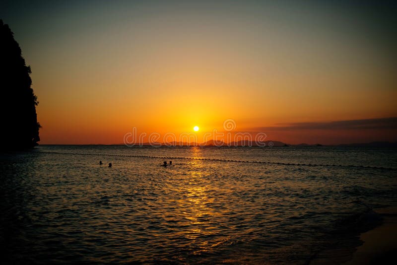 Os povos nadam no mar na noite no por do sol foto de stock Os povos nadam no mar na noite no por do sol foto de stock