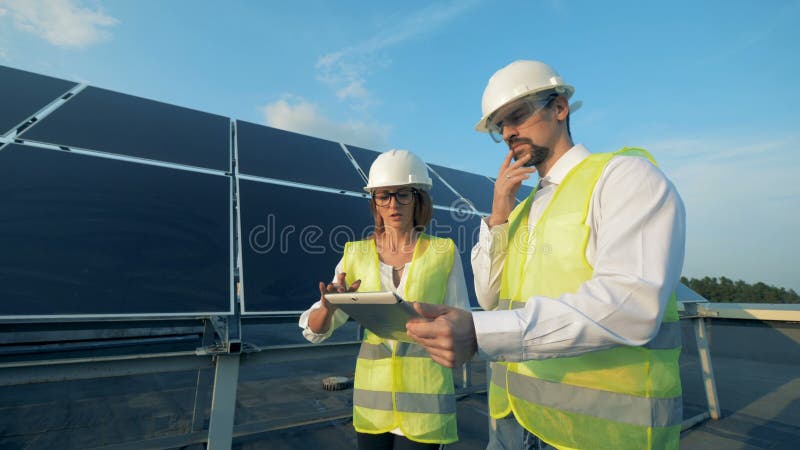 Os povos trabalham com uma tabuleta ao andar perto dos painéis solares, fim acima vídeos de arquivo Os povos trabalham com uma tabuleta ao andar perto dos painéis solares, fim acima vídeos de arquivo