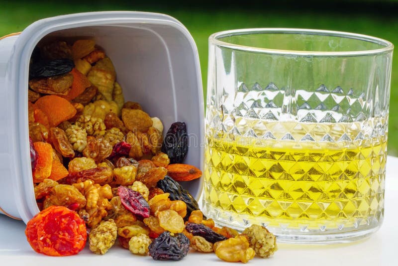 The pulses and dry fruits are poured out of the jar and a glass of alcohol is next to it. The pulses and dry fruits are poured out of the jar and a glass of alcohol is next to it