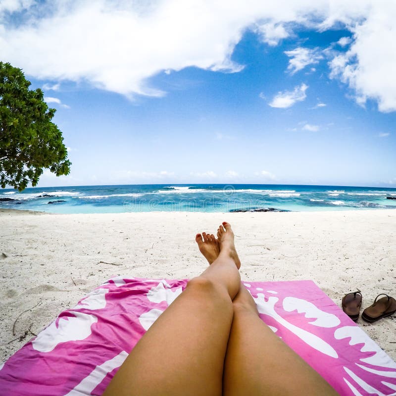 Os pés com pulverizador falsificado bronzeam-se no vadio do sol na praia tropical com p
