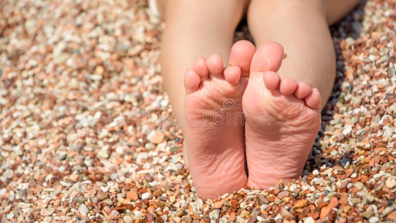 Os pés da criança na praia dos seixos fotografia de stock royalty free Os pés da criança na praia dos seixos fotografia de stock royalty free