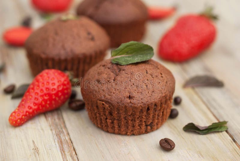 Os queques do chocolate com morango Mint as folhas sobre o deserto rústico de Gray Background Breakfast imagens de stock Os queques do chocolate com morango Mint as folhas sobre o deserto rústico de Gray Background Breakfast imagens de stock