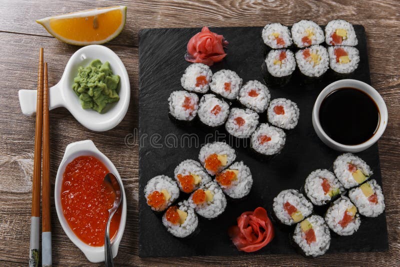 Os rolos e os ingredientes de sushi serviram em uma superfície de madeira fotografia de stock Os rolos e os ingredientes de sushi serviram em uma superfície de madeira fotografia de stock