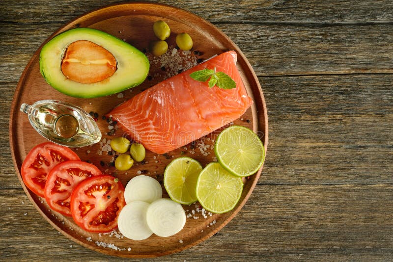Os salmões vermelhos da carne pescam, tomates, especiarias, limão, azeitonas verdes na mesa de cozinha de madeira imagens de stock royalty free Os salmões vermelhos da carne pescam, tomates, especiarias, limão, azeitonas verdes na mesa de cozinha de madeira imagens de stock royalty free