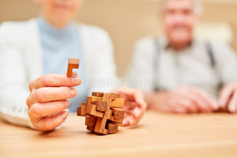Os sêniores estão fazendo um jogo do enigma com enigma de madeira imagem de stock Os sêniores estão fazendo um jogo do enigma com enigma de madeira imagem de stock