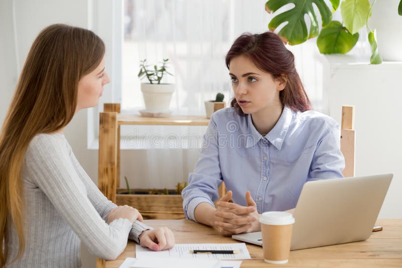 Os sócios fêmeas falam na tabela do escritório que discutem o contrato foto de stock Os sócios fêmeas falam na tabela do escritório que discutem o contrato foto de stock