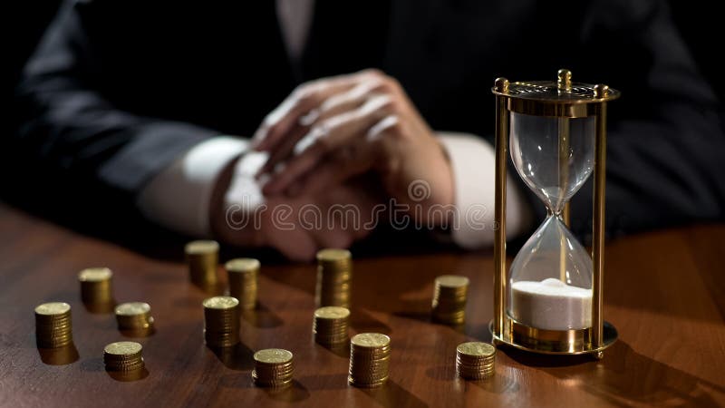Os tempos acima na ampulheta, homem de negócios contam perdas financeiras após o investimento imagens de stock royalty free Os tempos acima na ampulheta, homem de negócios contam perdas financeiras após o investimento imagens de stock royalty free