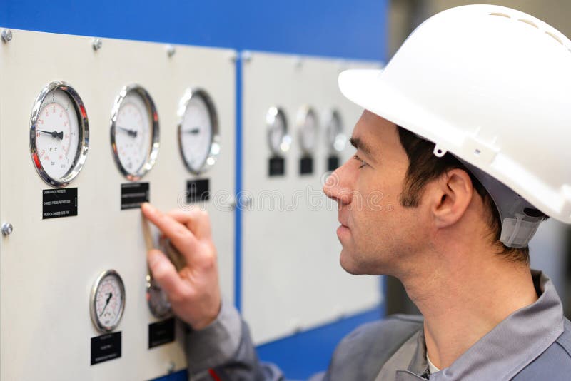 Os trabalhadores industriais leram os instrumentos de uma máquina imagens de stock Os trabalhadores industriais leram os instrumentos de uma máquina imagens de stock