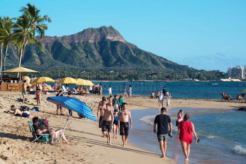 Os turistas que andam ao longo da linha costeira em Waikiki e em Diamond Head são uma estância turística popular e romântica em O foto de stock royalty free Os turistas que andam ao longo da linha costeira em Waikiki e em Diamond Head são uma estância turística popular e romântica em O foto de stock royalty free