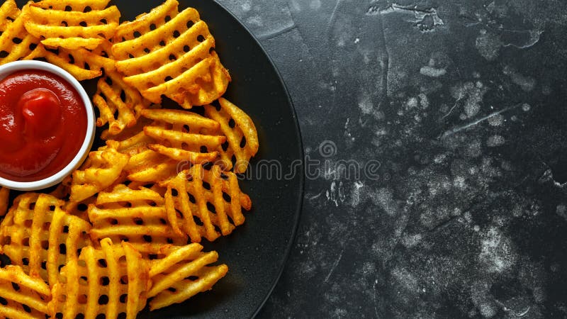 Crispy Potato Waffles Fries with Ketchup in a black plate. Crispy Potato Waffles Fries with Ketchup in a black plate.