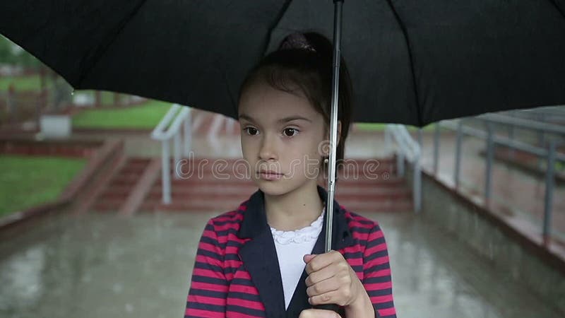 Osamotniona dziecko dziewczyna w deszczu z parasolem slo mo