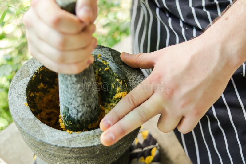 Blur, hands, pounding curry paste in rock mortar. Thai cooking. Blur, hands, pounding curry paste in rock mortar. Thai cooking.