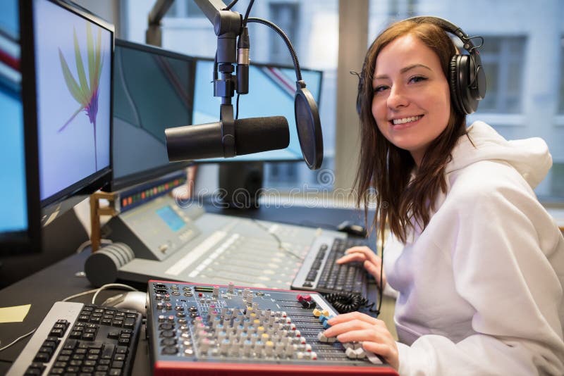 Ospite femminile sicuro che sorride nella stazione radio fotografia stock Ospite femminile sicuro che sorride nella stazione radio fotografia stock