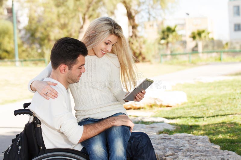Young disabled men and his girlfriend with digital tablet. Young disabled men and his girlfriend with digital tablet