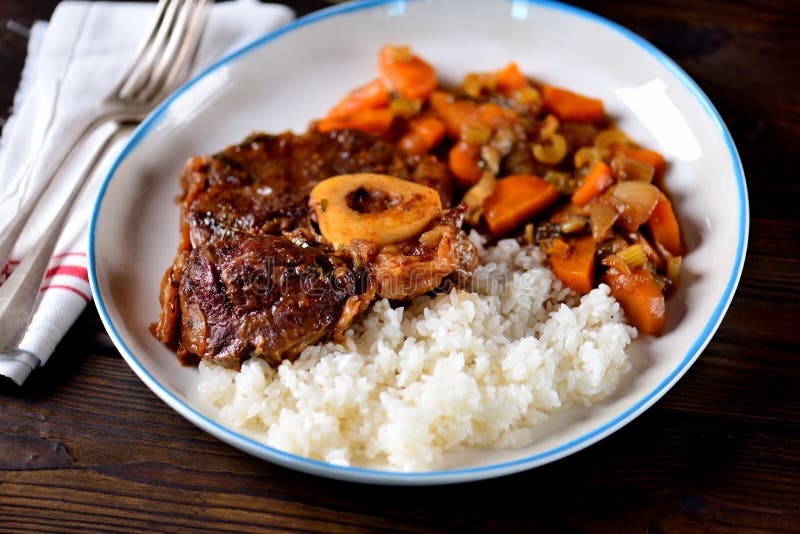 Osso buco beef stew with boiled rice in tomato sauce with onions, carrots, celery, garlic, rosemary and laurel leaves. food. Osso buco beef stew with boiled rice in tomato sauce with onions, carrots, celery, garlic, rosemary and laurel leaves. food