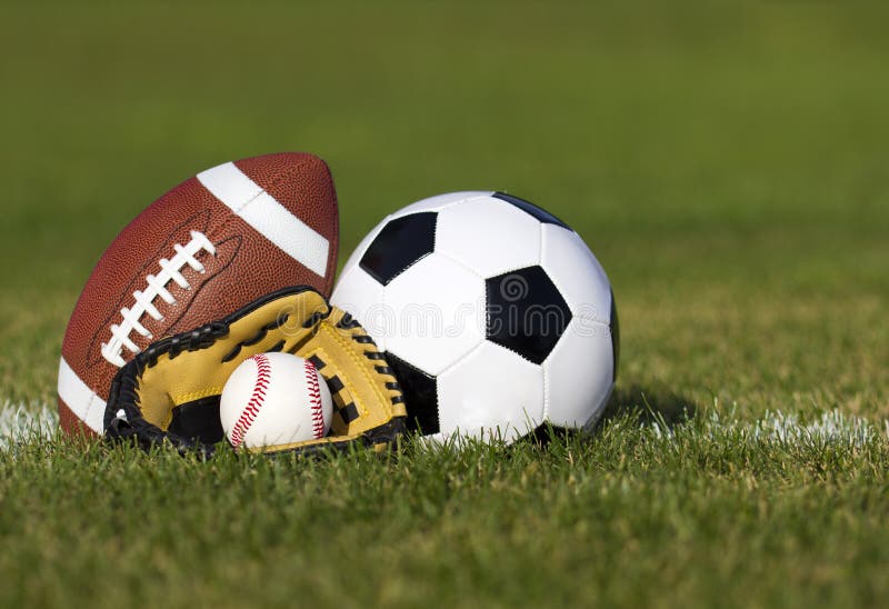 Ostenta bolas no campo com linha de jardas. Bola de futebol, futebol americano e basebol na luva amarela na grama verde