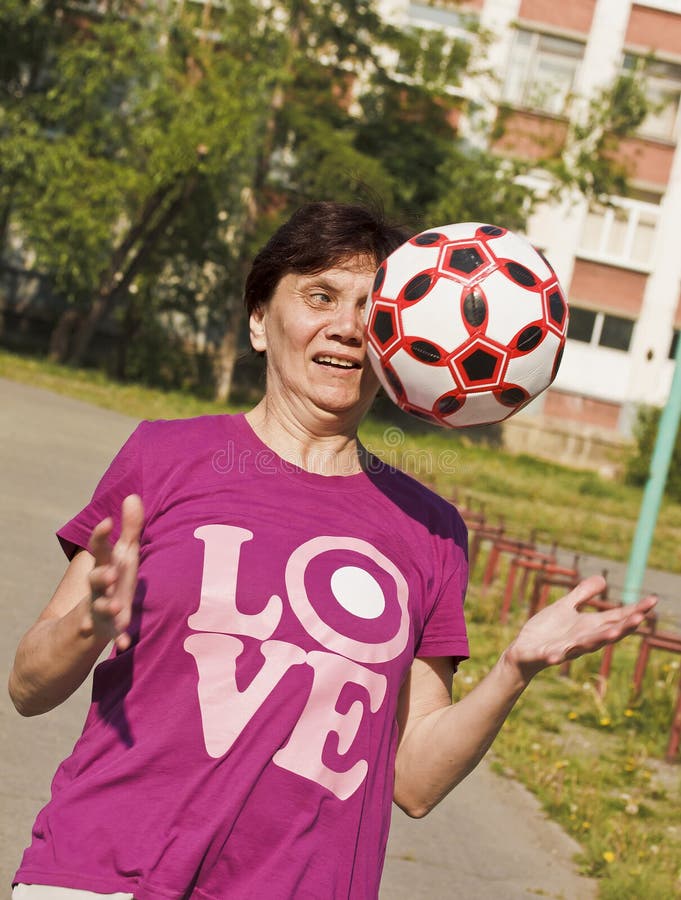 Ostentar uma mulher adulta tenta entusiasticamente travar a bola jogada para ela Jogando o futebol fotos de stock Ostentar uma mulher adulta tenta entusiasticamente travar a bola jogada para ela Jogando o futebol fotos de stock