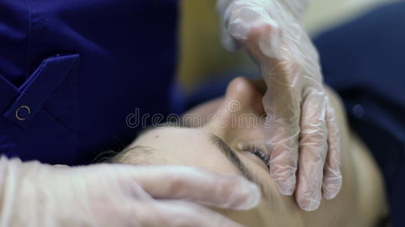Osteopatisk läkare håller hand i handskar på ansiktet lager videofilmer