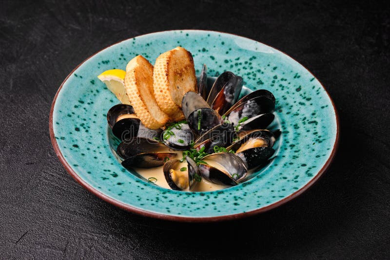 Ostriche in salsa di crema su piastra blu su fondo nero. Ostriche in salsa di crema su piastra blu su fondo di calcestruzzo nero